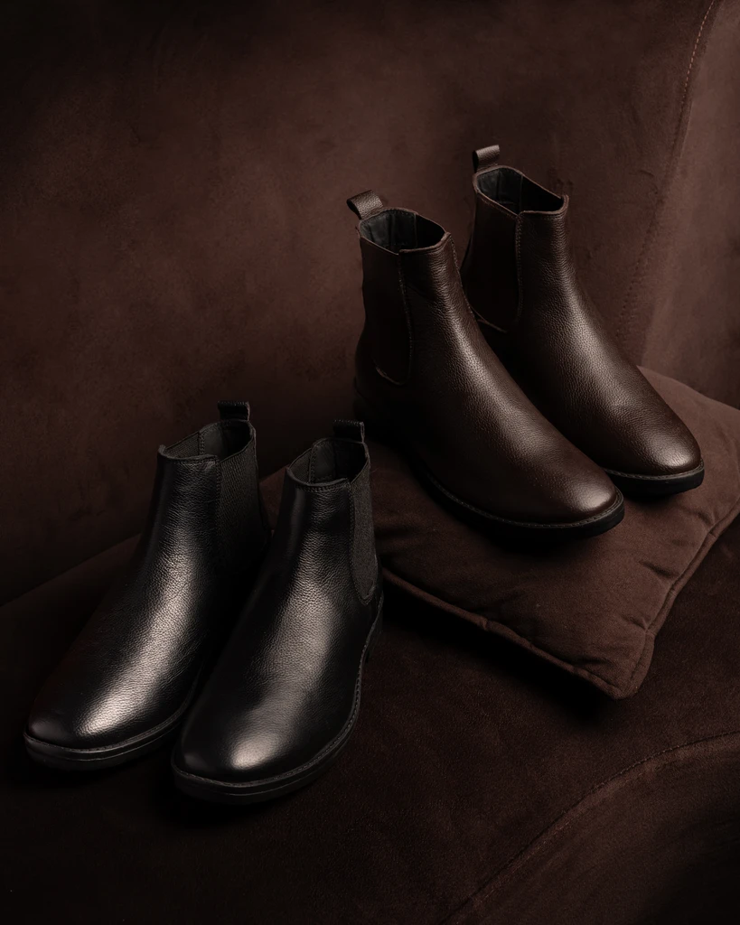 Black and brown Chelsea boots on brown upholstery